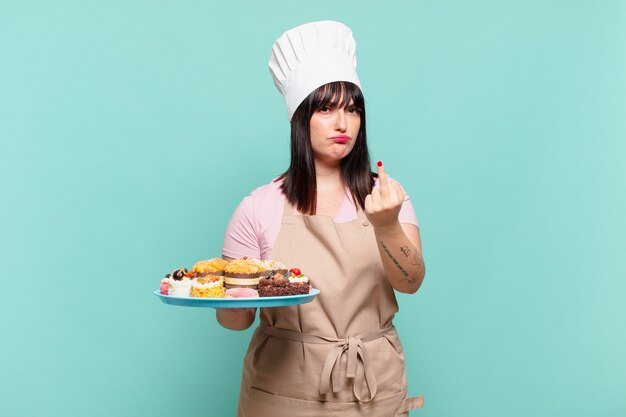 Young chef woman feeling angry, annoyed, rebellious and aggressive, flipping the middle finger, fighting back