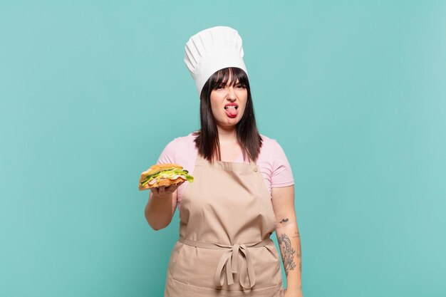 Young chef woman feeling disgusted and irritated, sticking tongue out, disliking something nasty and yucky