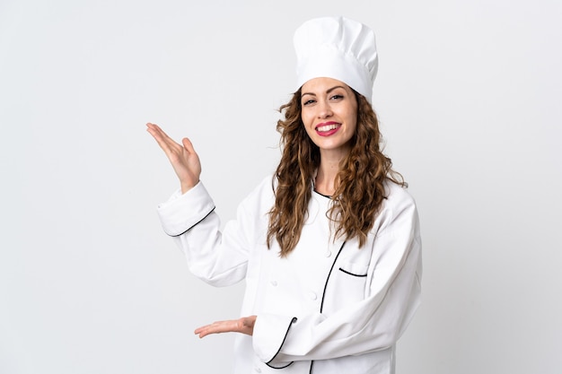 Young chef woman isolated on white background extending hands to the side for inviting to come