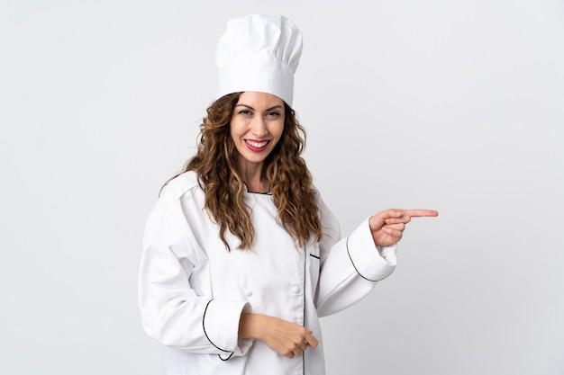 Young chef woman isolated on white background pointing finger to the side