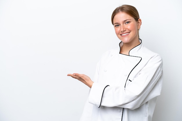 Young chef woman isolated on white background presenting an idea while looking smiling towards