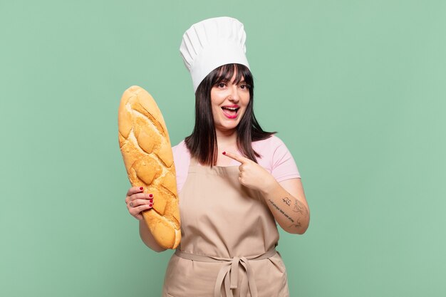 Young chef woman looking excited and surprised pointing to the side and upwards to copy space