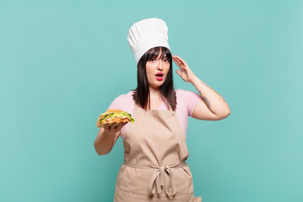 Young chef woman looking happy, astonished and surprised, smiling and realizing amazing and incredible good news