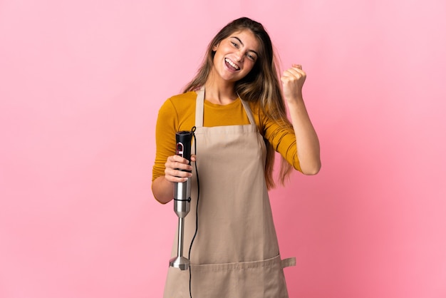 Young chef woman using hand blender isolated