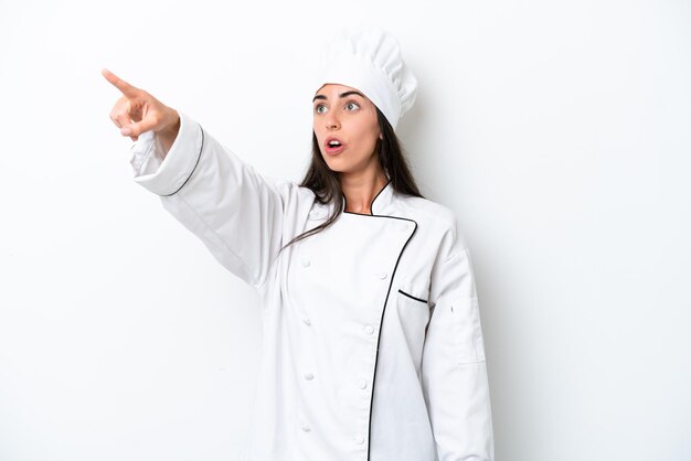Donna giovane chef su sfondo bianco che punta lontano