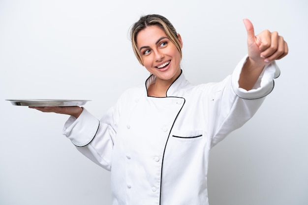 Photo young chef woman with tray isolated on white background giving a thumbs up gesture