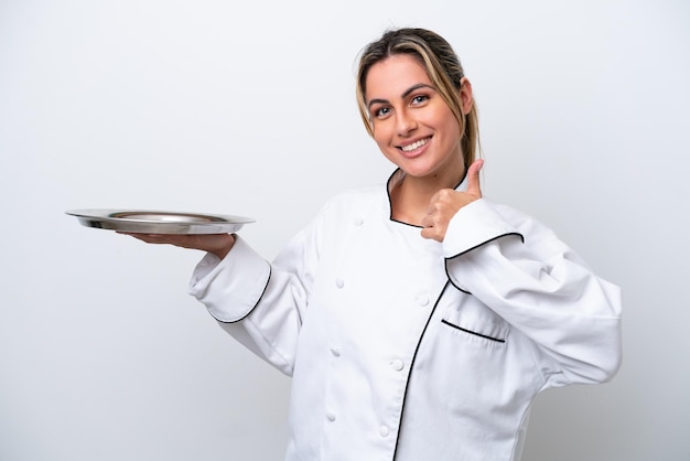 Young chef woman with tray isolated on white background giving a thumbs up gesture