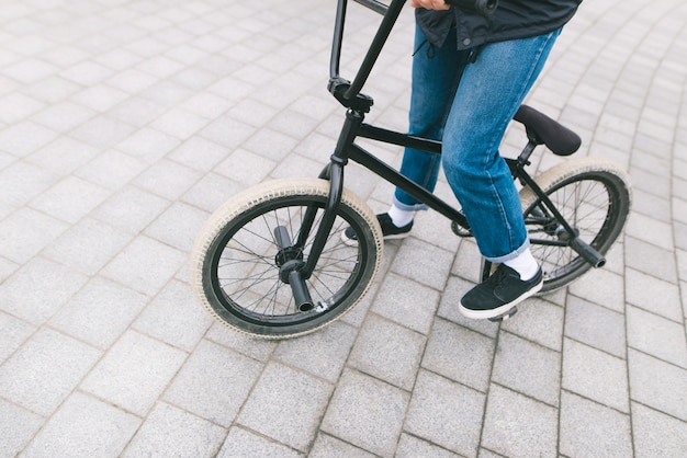 A young chelovek sits on a BMX bike. BMX with legs close-up. BMX concept. Street culture