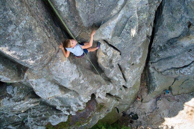 Young child boy climbing steep wall of rocky mountain Kid climber overcomes challenging route Engaging in extreme sport concept