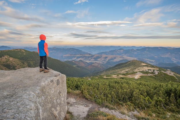 Фото hiker мальчика маленького ребенка стоя в горах наслаждаясь взглядом изумительного ландшафта горы.