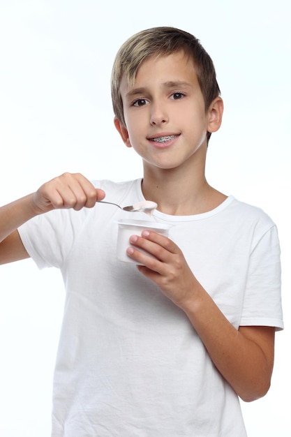 Маленький ребенок ест йогурт, изолированный на белом