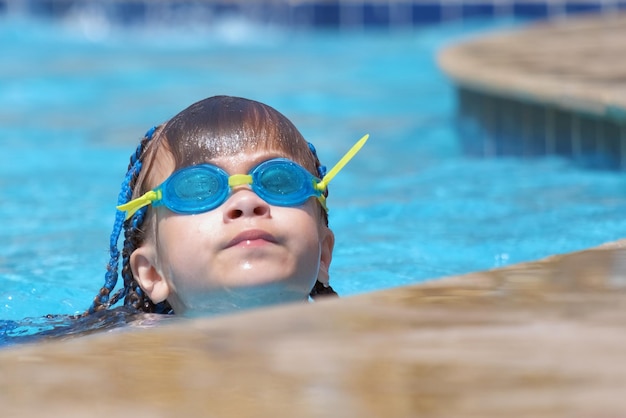 Young child girl in goggles exercises swimming in blue pool water summer recreation activity concept