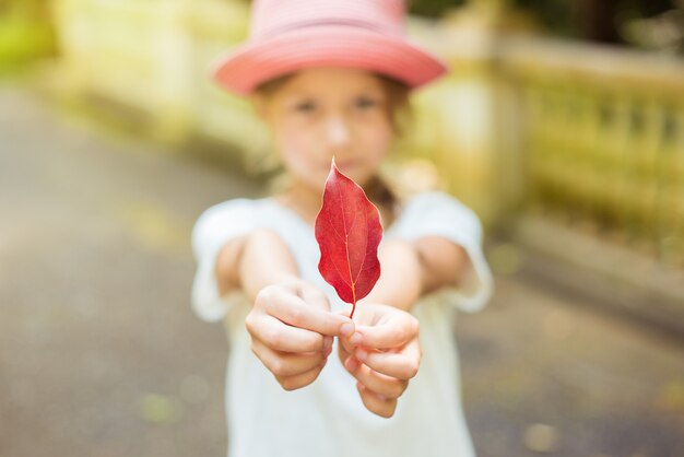 Young child girl holding a red leaf