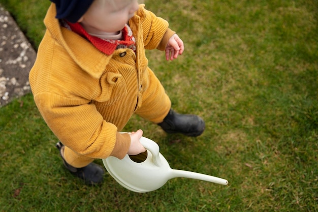 じょうろで庭の散水植物を手伝っている幼い子供