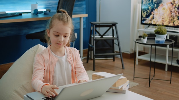 Маленький ребенок с помощью клавиатуры на ноутбуке для домашних заданий и онлайн-курсов