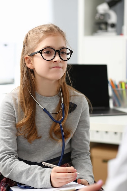 Young child wants to be doctor write advices on paper wear stethoscope equipment on neck