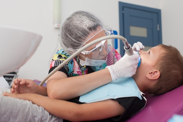 Photo young children's doctor dentist treats teeth with different devices