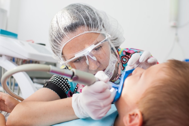 Photo young children's doctor dentist treats teeth with different devices