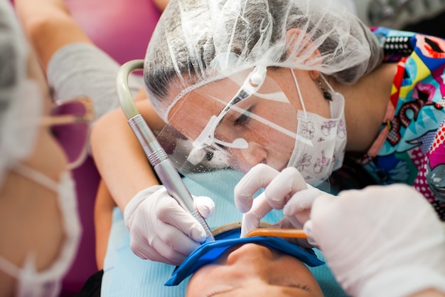 Photo young children's doctor dentist treats teeth with different devices