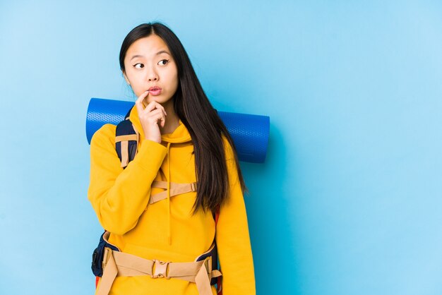 Young chinese backpacker woman isolated looking sideways with doubtful and skeptical expression.