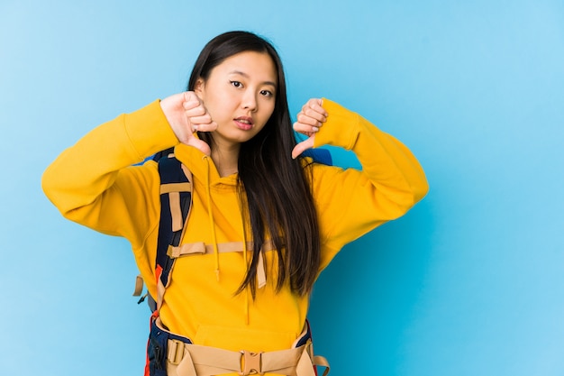 Young chinese backpacker woman isolated showing thumb down and expressing dislike.