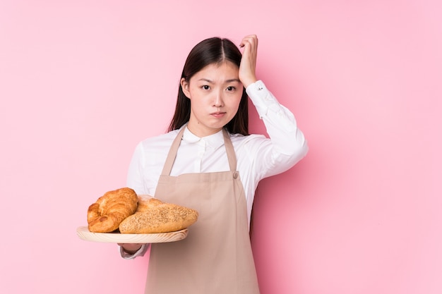 Young chinese baker woman isolated being shocked, she has remembered important meeting.