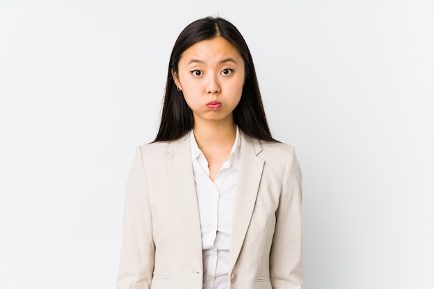 Young chinese business woman isolated blows cheeks, has tired expression. Facial expression concept.