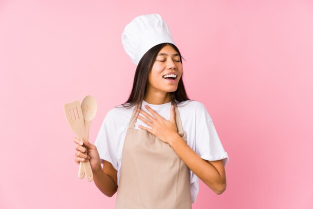 Young chinese chef woman isolated laughs out loudly keeping hand on chest.