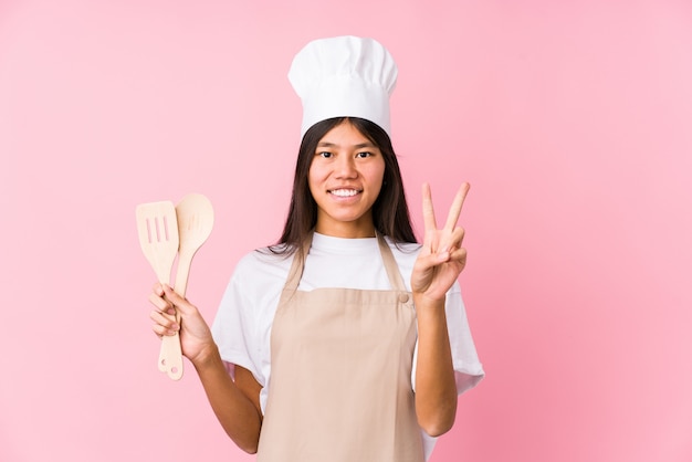 Young chinese chef woman isolated showing number two with fingers.
