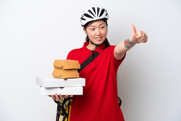 Young Chinese delivery woman taking takeaway food isolated on white background giving a thumbs up gesture