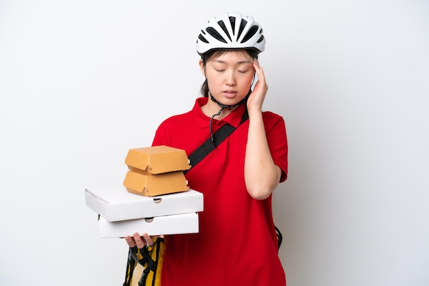 Young Chinese delivery woman taking takeaway food isolated on white background with headache