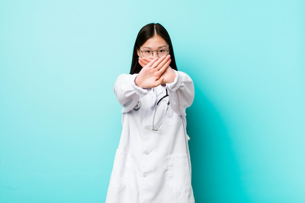 Young chinese doctor woman doing a denial gesture