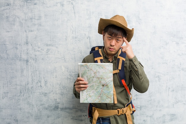 Young chinese explorer man holding a map thinking about an idea