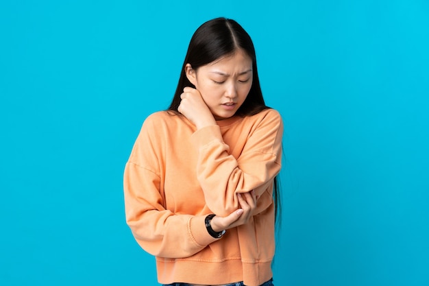 Young Chinese girl over blue with pain in elbow