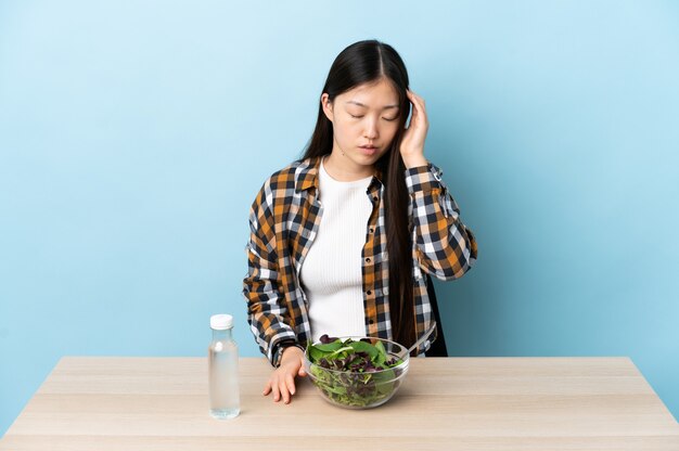 写真 頭痛とサラダを食べる中国の若い女の子