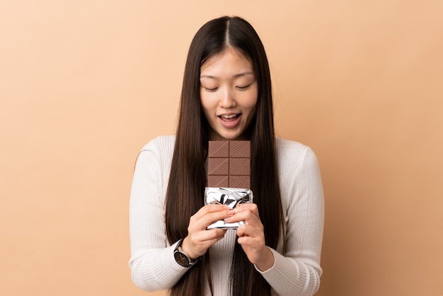 Young Chinese girl eating a chocolate tablet