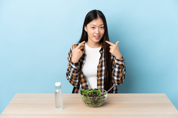 Young Chinese girl eating a salad giving a thumbs up gesture