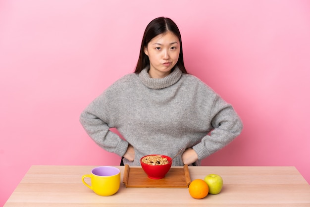 Young Chinese girl  having breakfast in a table angry