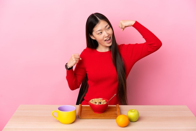 Young Chinese girl  having breakfast in a table celebrating a victory