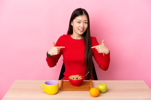 Young Chinese girl  having breakfast in a table proud and self-satisfied