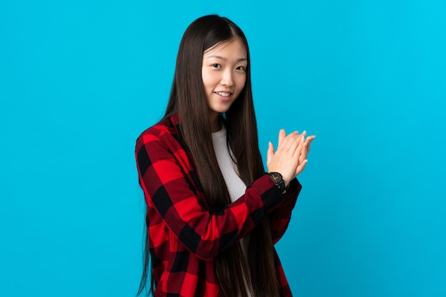 Young Chinese girl over isolated blue background applauding