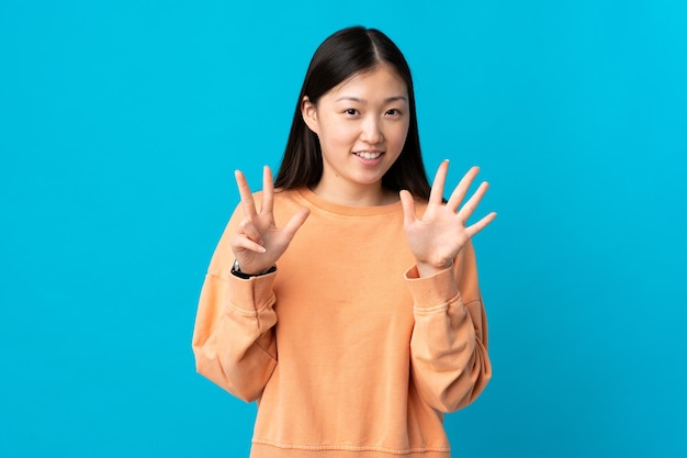 Young Chinese girl over isolated blue background counting eight with fingers