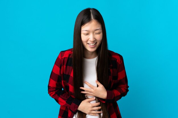 Giovane ragazza cinese su sfondo blu isolato sorridente molto