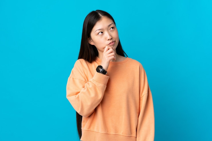 Photo 孤立した青い壁と見上げる中国の少女