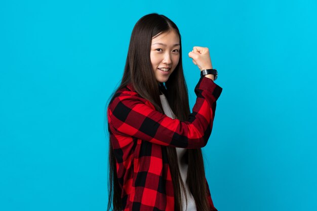 Young Chinese girl over isolated doing strong gesture