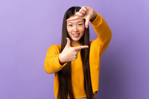 Young Chinese girl over isolated purple focusing face. Framing symbol