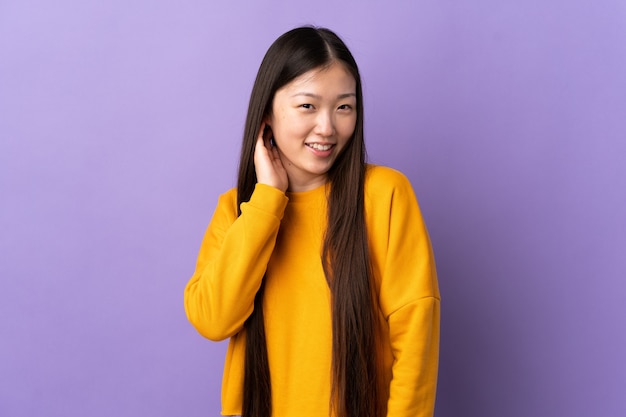 Young Chinese girl over isolated purple laughing