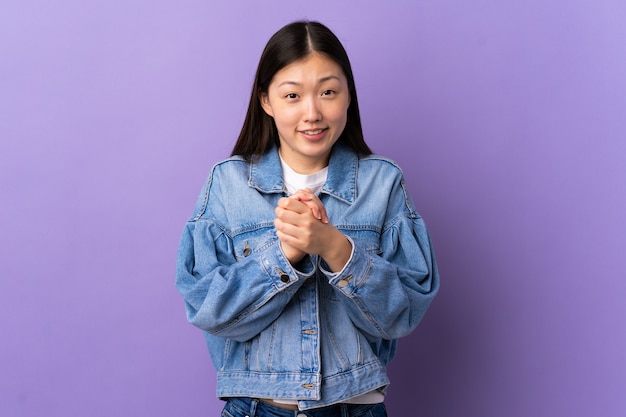 Young chinese girl over isolated purple laughing