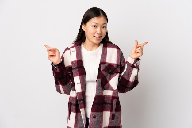 Foto giovane ragazza cinese su sfondo bianco isolato che punta il dito ai laterali e felice