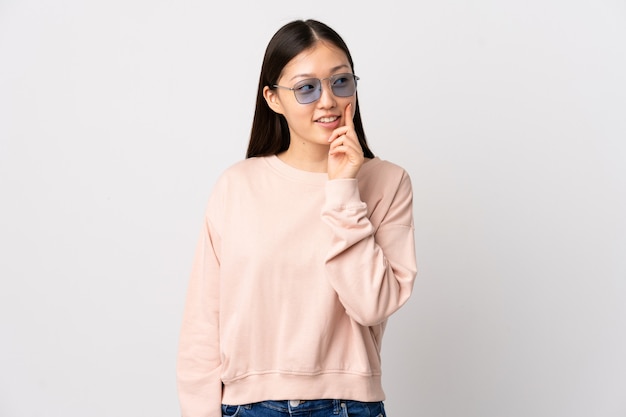 Young Chinese girl over isolated white background thinking an idea while looking up